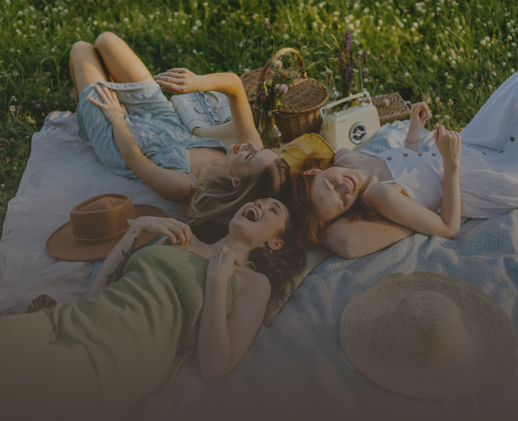 Friends laughing together on a picnic blanket in golden afternoon light